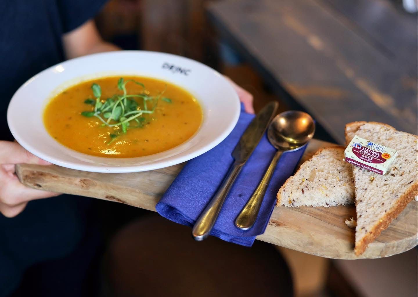 Homemade soup with fresh bread on wooden board at DRINC Ramsbottom